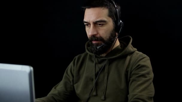 Siyah Arka Planda Sakallı Kulaklıklı Mikrofonlu Bir Adam Laptopla Çalışıyor — Stok video