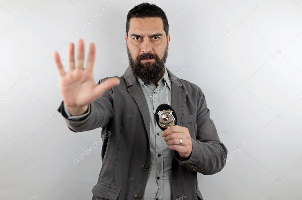 Bearded detective with serious face showing police badge and making stop sign with hand. Crime concept.