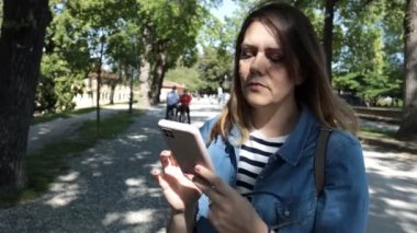 Parktaki güzel sarışın kız akıllı telefondan yazı yazıyor..