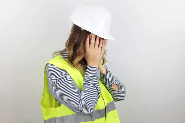 Yansıtıcı ceket giyen kadın mimar ve ağlarken yüzünü ellerle kapatan üzgün yüzlü kasklı. depresyon kavramı.