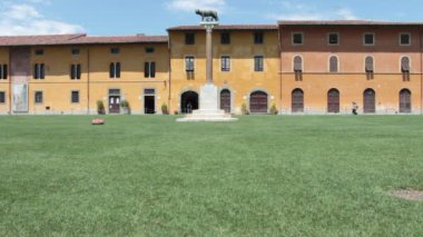 Capitoline dişi kurt, arka planda Pisa 'daki Piazza dei Miracoli' deki Palazzo Dell 'Opera del Duomo.