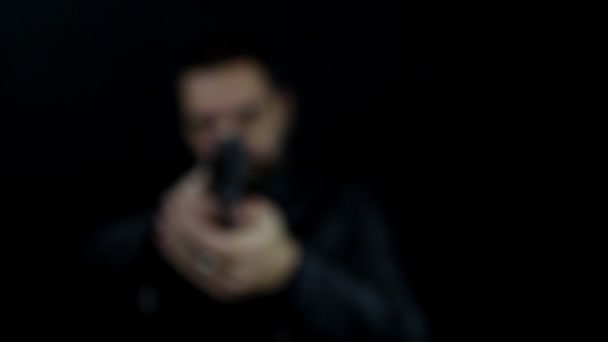 一个人从黑暗中走出来 手里拿着枪指着摄像机 枪膛上装着枪管 穿便衣的黑帮 — 图库视频影像