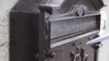 Yakından bakınca, bir kadın posta kutusuna bir mektup bırakıyor.