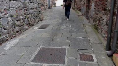 Orta Çağ 'ın Vicopisano, Pisa, İtalya' sında bir kız şehir merkezinde yürüyor.