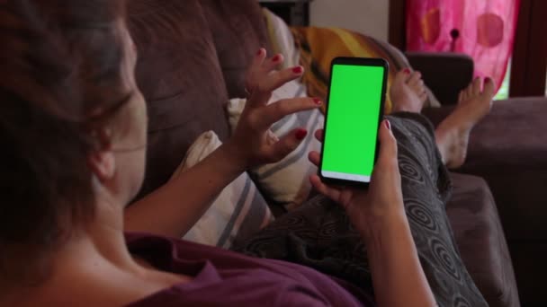 Uma Menina Deitada Sofá Digitando Smartphone Com Uma Tela Verde — Vídeo de Stock