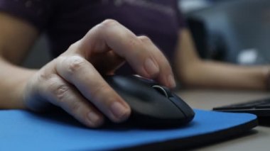 Woman works on the computer using the mouse. Close up hand.