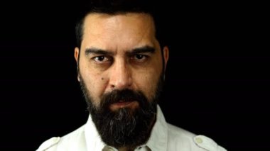 Siyah arka planda sakallı bir adam işaret parmağını ağzının önünde tutarak sessizlik işareti yapıyor. Sessizlik kavramı