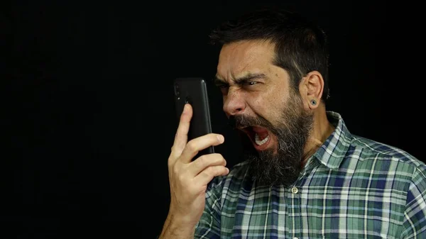 Sakallı bir adam telefonda konuşuyor. Çığlıklar atıyor ve bağırıyor. Öfkeli ve öfkeli..