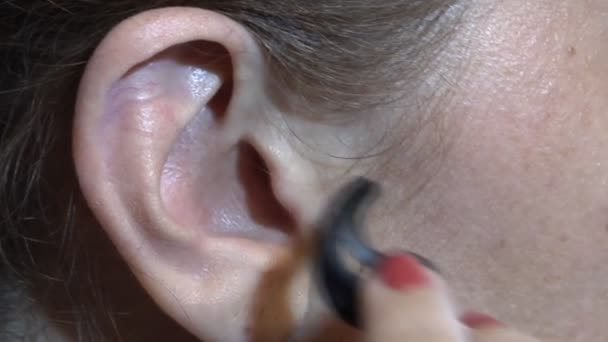 Großaufnahme Setzt Eine Frau Das Headset Auf Ihr Ohr Zuzuhören — Stockvideo