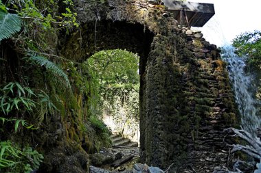 Patlayıcı ve mühimmat üretimi için terk edilmiş eski fabrikalar arasındaki eski taş kemer. Mulina di Stazzema 'daki Calcaferro arkeolojik maden sahası, Lucca, İtalya.