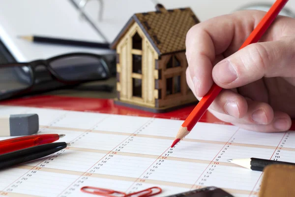 Entrada en el calendario con lápiz, papelería y casita Imagen de archivo