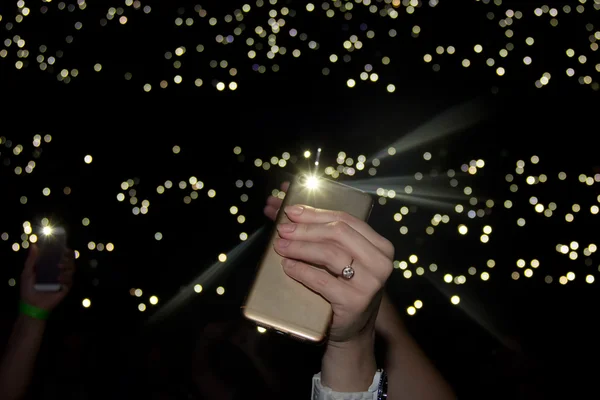 Hand in concert with flashlight shines phone Royalty Free Stock Images