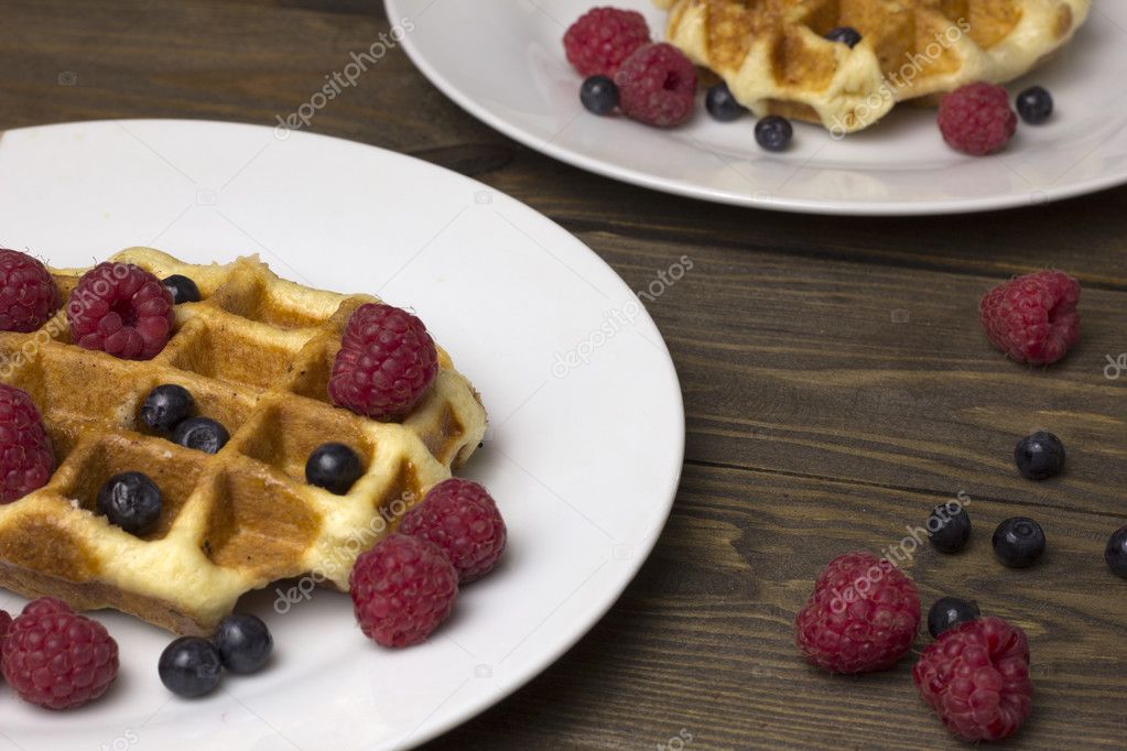 two plates of waffles with berries on the table