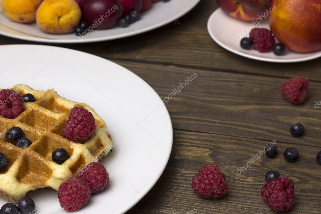 Two plates of waffles and berries on a wooden table