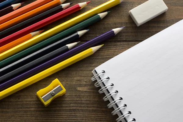 Crayons, notebook , eraser and pencil sharpener — Stock Photo, Image