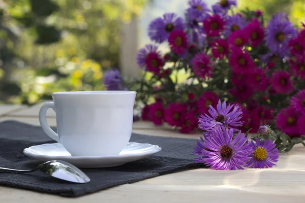 Tasse de thé et un bouquet de fleurs pourpres et pourpres — Photo