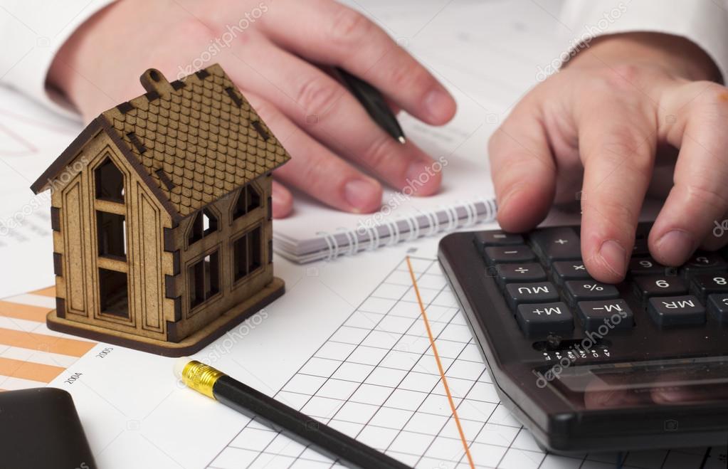 house and the man's hand considers on the calculator