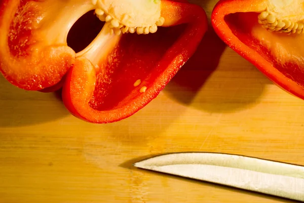 Half of pepper on the wooden board with knife — Stock Photo, Image