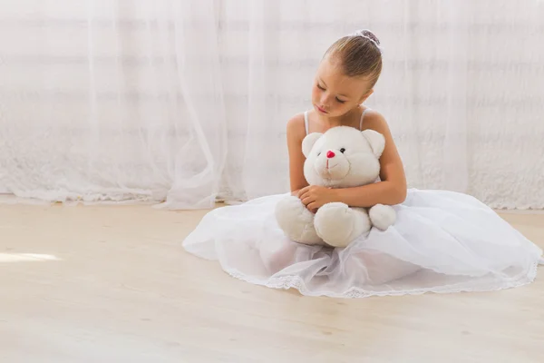 Süße kleine Balerina umarmt ihren Teddybär — Stockfoto
