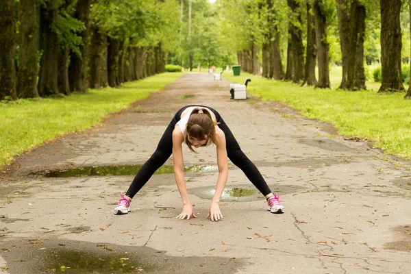 Młoda kobieta nagrzewa się w parku przed joggingu — Zdjęcie stockowe