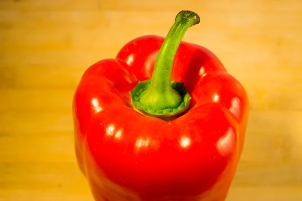 Fresh red bell pepper on an aged wooden board — Stock Photo, Image
