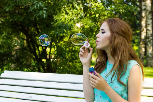 Vakker kvinne som blåser bobler i sola, utendørs – stockfoto