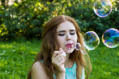 Güzel kadın üfleme kabarcıklar yaz aylarında açık havada göl yakınındaki