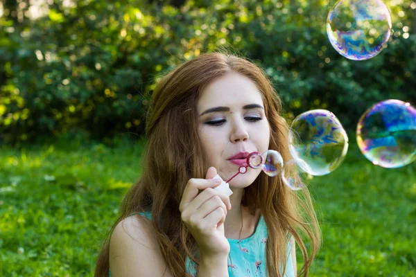 Vakker kvinne som blåser bobler om sommeren nær innsjøen, utendørs – stockfoto