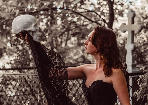 Красивая девушка в стиле глэм-рока в черном нижнем белье с фальшивой головой черепа — стоковое фото