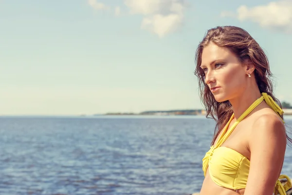 Vacker kvinna i bikini poserar nära blå havet — Stockfoto