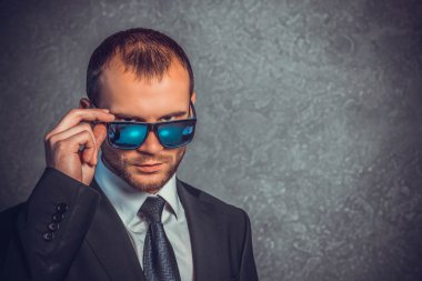 Acımasız seksi işadamları kravat ve duvara yakın duran güneş gözlüğü ile takım elbiseli. Patron kavramı.