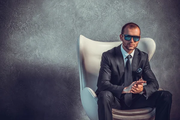Brutali uomini d'affari sexy in abito con cravatta e occhiali da sole seduti sulla sedia. Concetto di capo . — Foto Stock