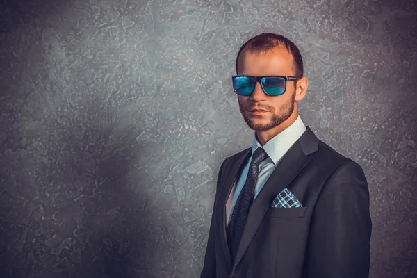 Brutali uomini d'affari sexy in abito con cravatta e occhiali da sole in piedi vicino al muro. Concetto di capo . — Foto Stock