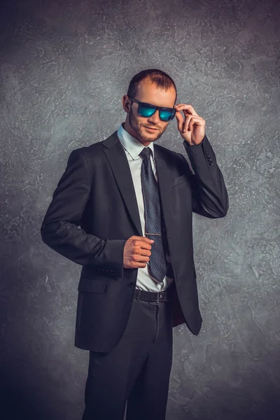 Brutali uomini d'affari sexy in abito con cravatta e occhiali da sole in piedi vicino al muro. Concetto di capo . — Foto Stock