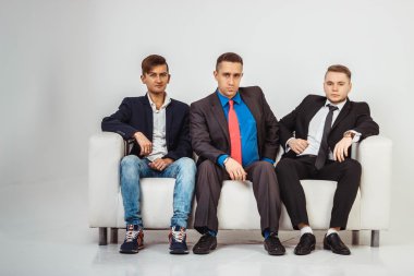 Takım elbiseli beyaz arka plan üzerinde izole kanepede oturan üç işadamı