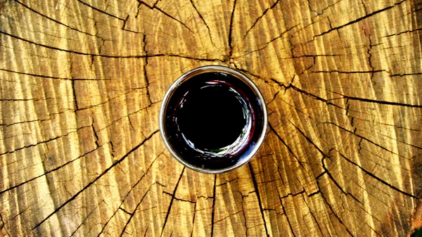 Ahşap bir kütüğün üzerinde koyu kırmızı içecek bir bardak