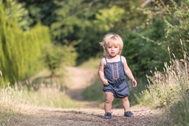 Kız bebek yeşil orman yolu üzerinde yürüyor