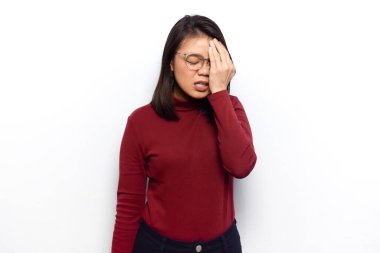 Baş ağrısı ve yüz hareketi kavramı. Genç güzel Asyalı kadınlar beyaz arka planda izole edilmiş kırmızı gömlek giyerler.