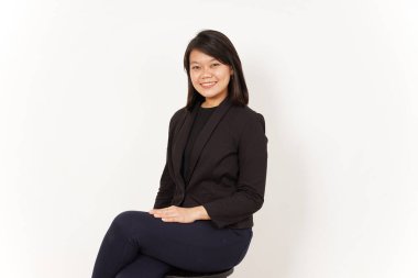 Siyah takım elbiseli güzel bir Asyalı kadın beyaz arka planda izole edilmiş kameraya bakıyor.