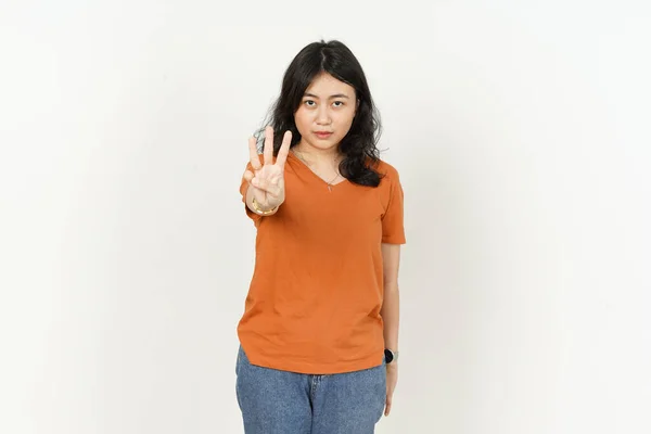 オレンジ色のTシャツを着た美しいアジア人女性が白い背景に孤立した3本の指を示す — ストック写真