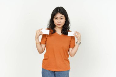 Beyaz arka planda turuncu tişört giyen Asyalı güzel bir kadının boş kredi kartını gösteriyor.