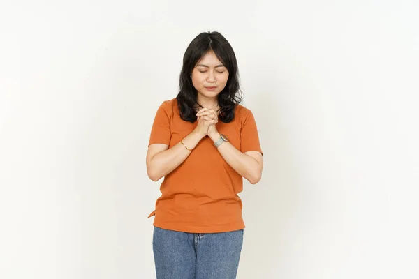 白い背景に孤立したオレンジのTシャツを着た美しいアジア人女性の祈りのジェスチャー — ストック写真