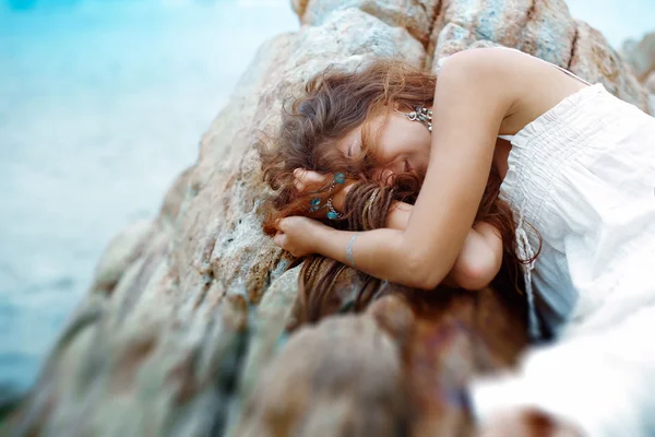 Schöne junge Frau schläft auf den Felsen am Strand — Stockfoto
