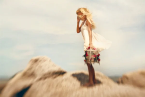 Blurry image of beautiful blonde girl with bird cage on the stones Stock Image