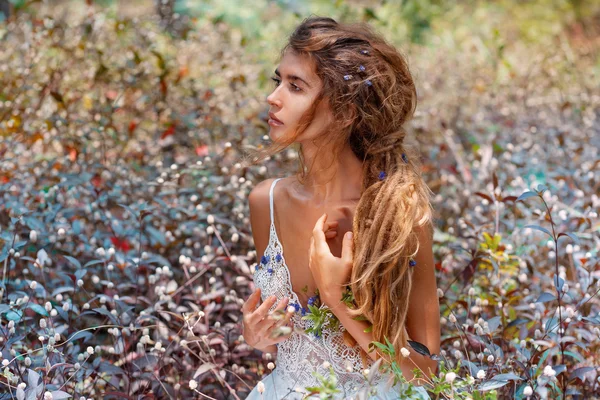 Sensual boho woman in white dress sitting on flower field — Stock Photo, Image