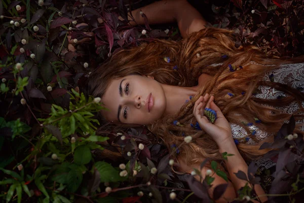 Piękna dziewczyna leżąc na trawie z kwiatami — Zdjęcie stockowe