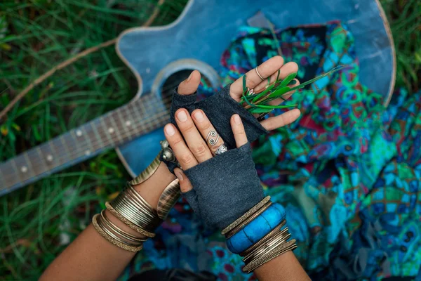 Закрыть фото цыганских рук с гитарой на зеленой траве — стоковое фото