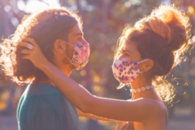 Gün batımında dışarıda maske takan genç çift.