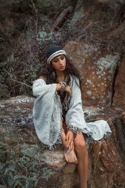 Güzel genç çingene tarzı bir kadın, açık havada kırmızı gülleri var.