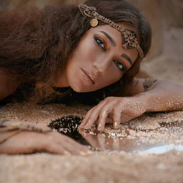 Menina bonita em jóias étnicas e espelho coberto de areia — Fotografia de Stock